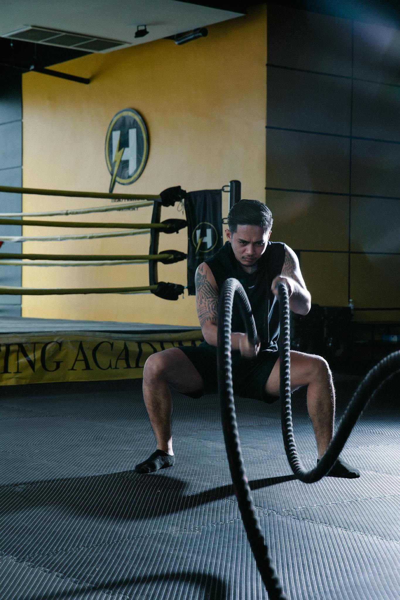 A man intensely performing battle rope exercises in a modern gym.