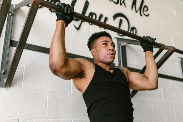 Athletic man doing pull-ups in a gym setting, showcasing strength and fitness.