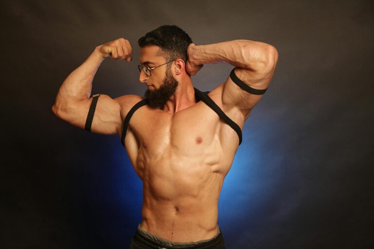 Muscular bearded man flexing in a studio shoot, showcasing fitness and strength.